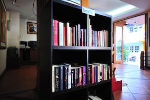 Uma estante com um letreiro que diz 'Empréstimo Gratuito', livros e uma pequena planta.