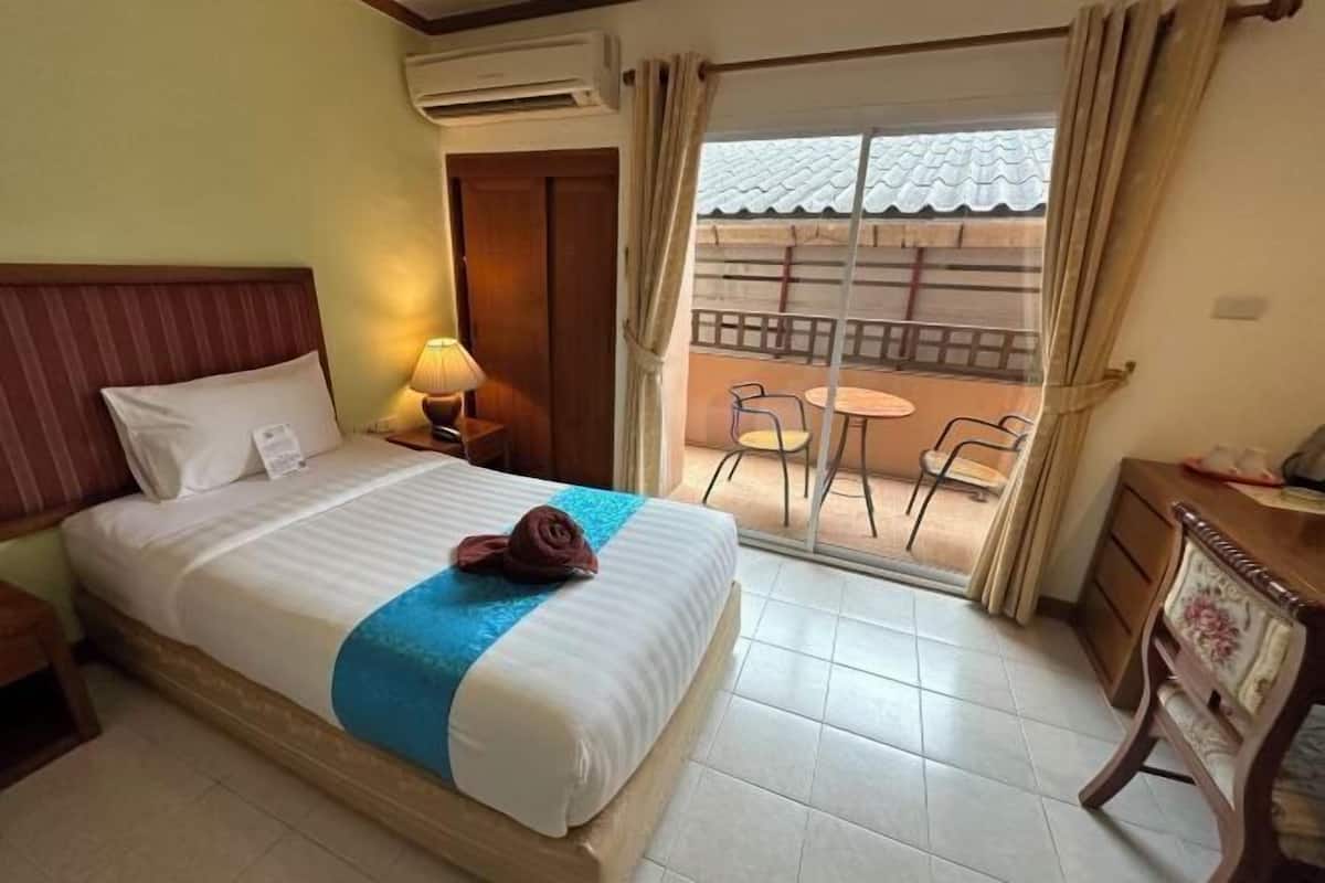 Quarto de hotel com cama, mesa de cabeceira, escrivaninha, cadeira e varanda com vista.
