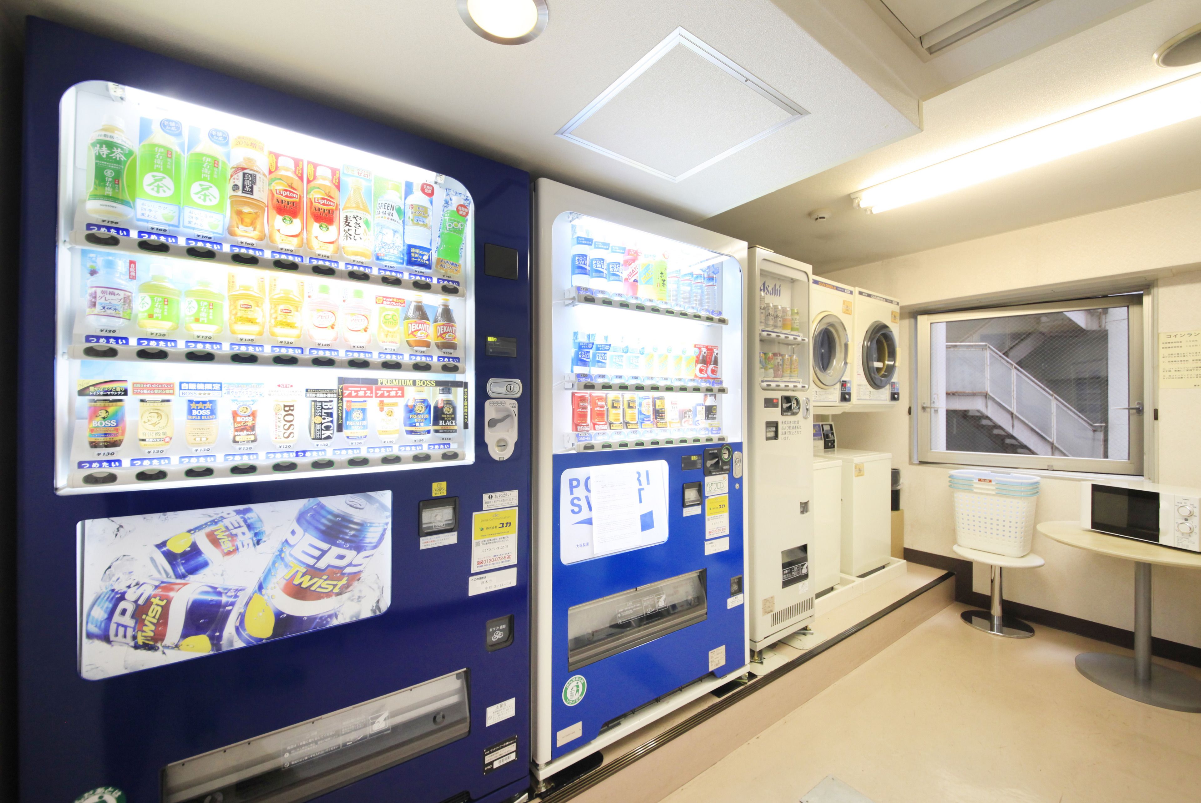 A vending machine area with various beverage options and a laundry machine.