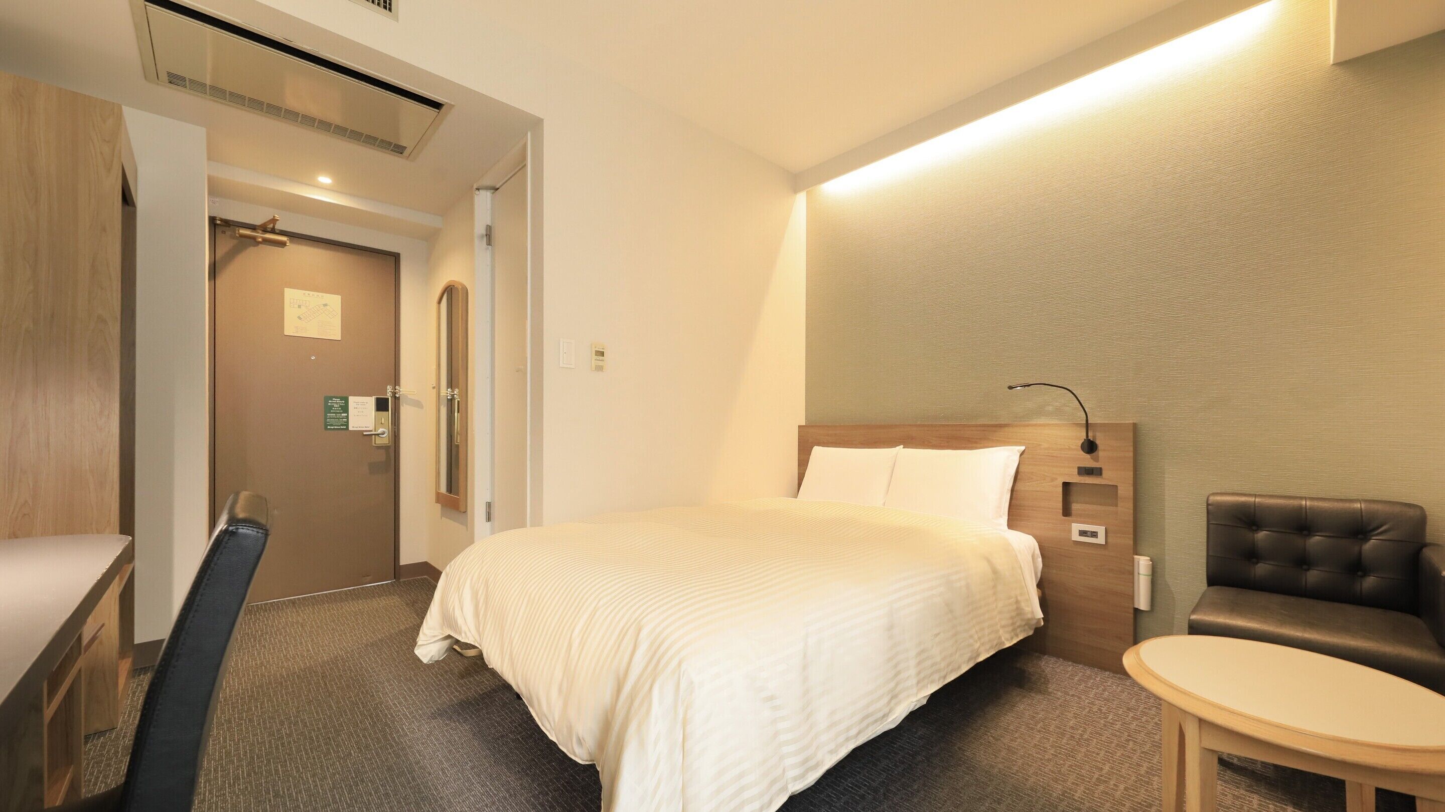 Una habitación de hotel con una cama, un escritorio, una silla y una mesita.