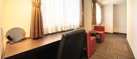 A hotel room with a desk, two chairs, a small table, and a mirror.