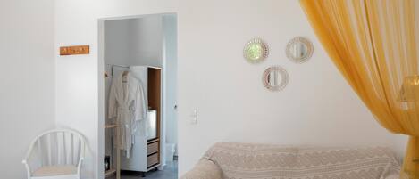 A bedroom with a bed, a chair, a wardrobe, and a mirror on the wall.