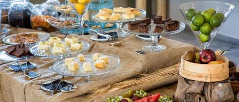 A buffet table with various food items including fruits, desserts, and pastries.