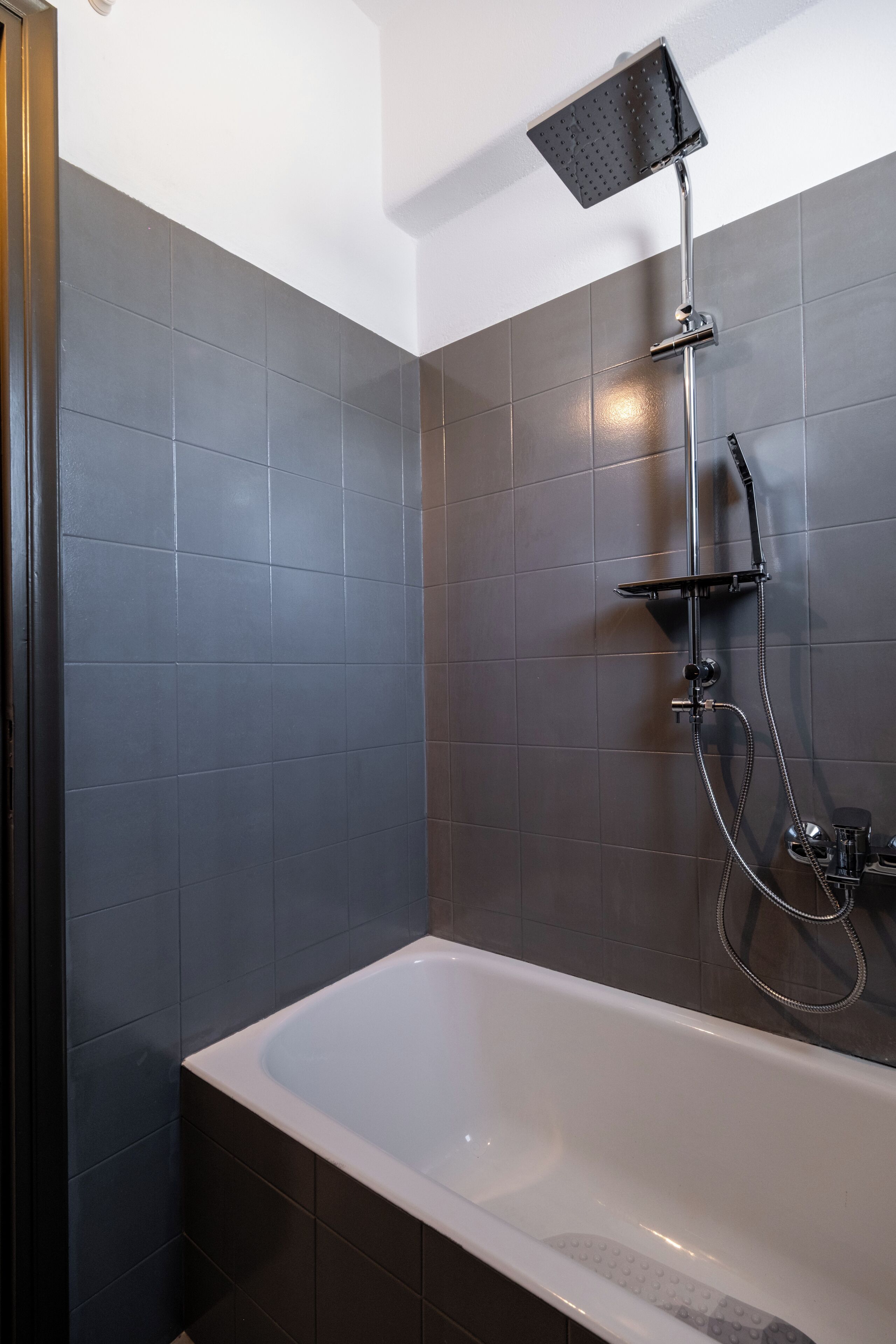 Un bagno moderno con vasca, doccia dotata di soffione a mano e rubinetto a parete.