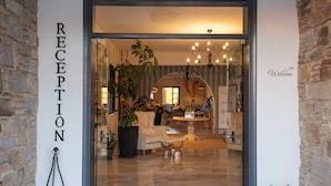 A hotel reception area with a modern design, featuring a reception desk, a chandelier, and a welcome sign. - Parosland Hotel (Paros)