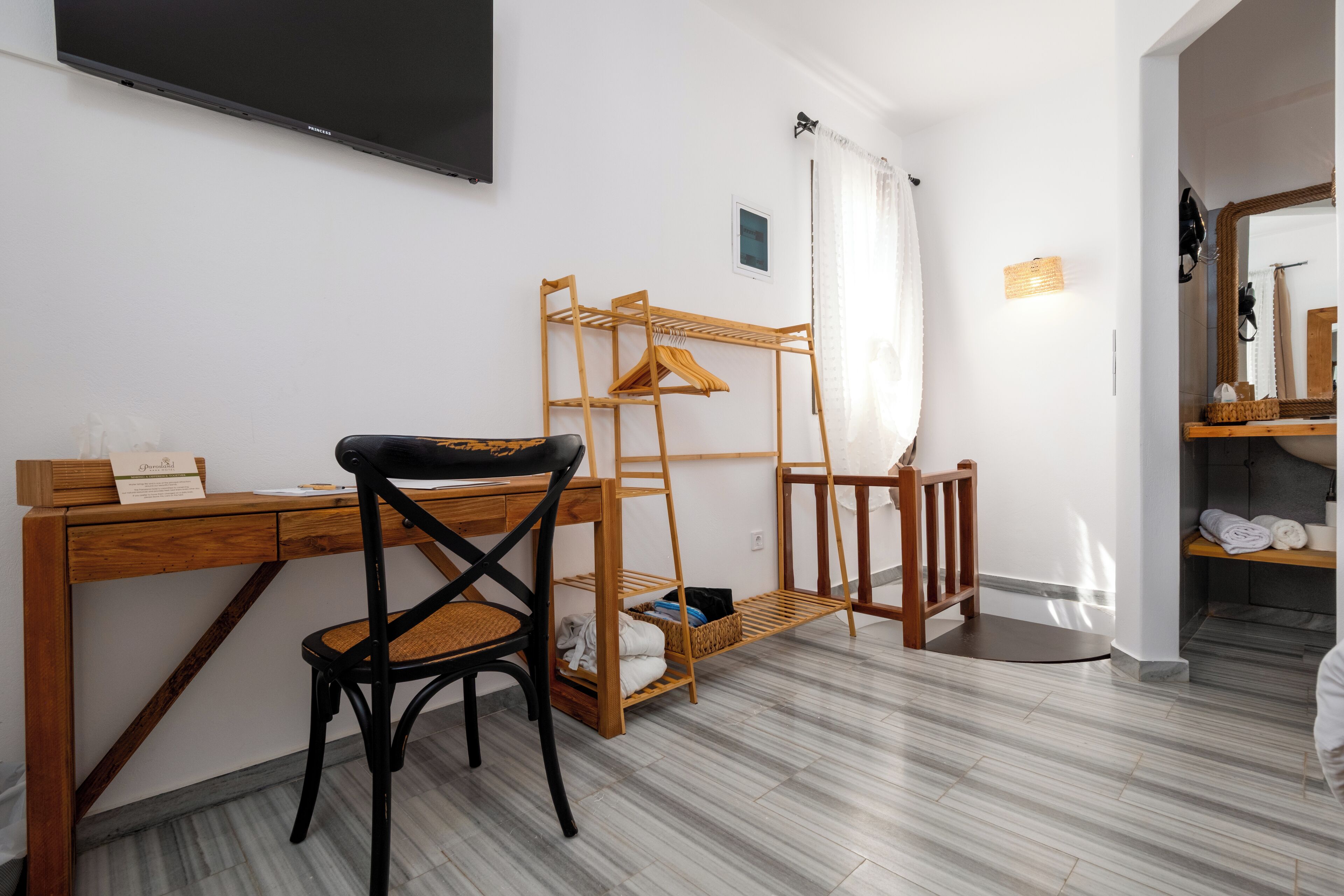 A room with a wooden desk, a chair, a bunk bed with a ladder, a small shelf, and a mirror.