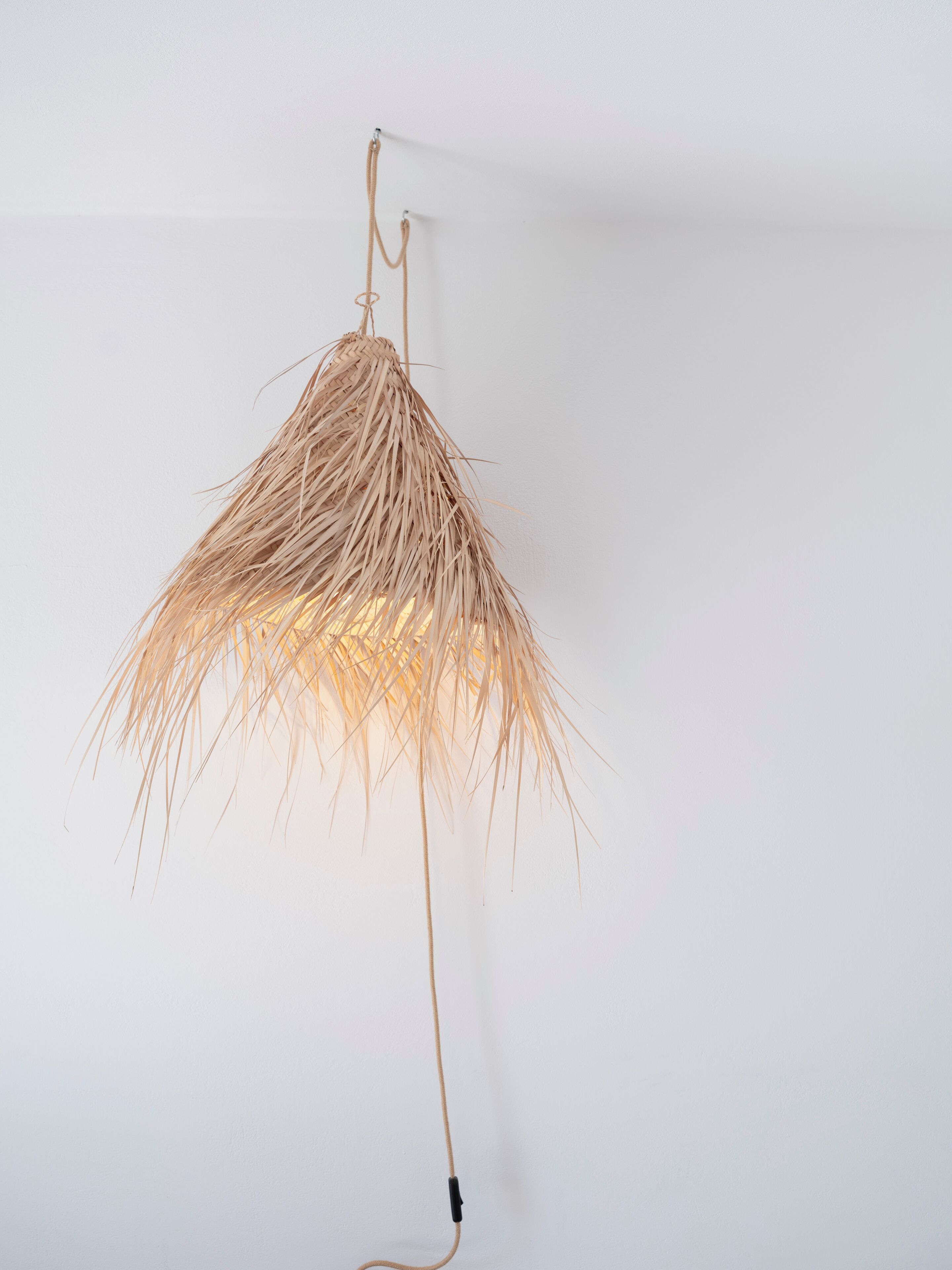 A hanging light fixture with a woven, natural material design.