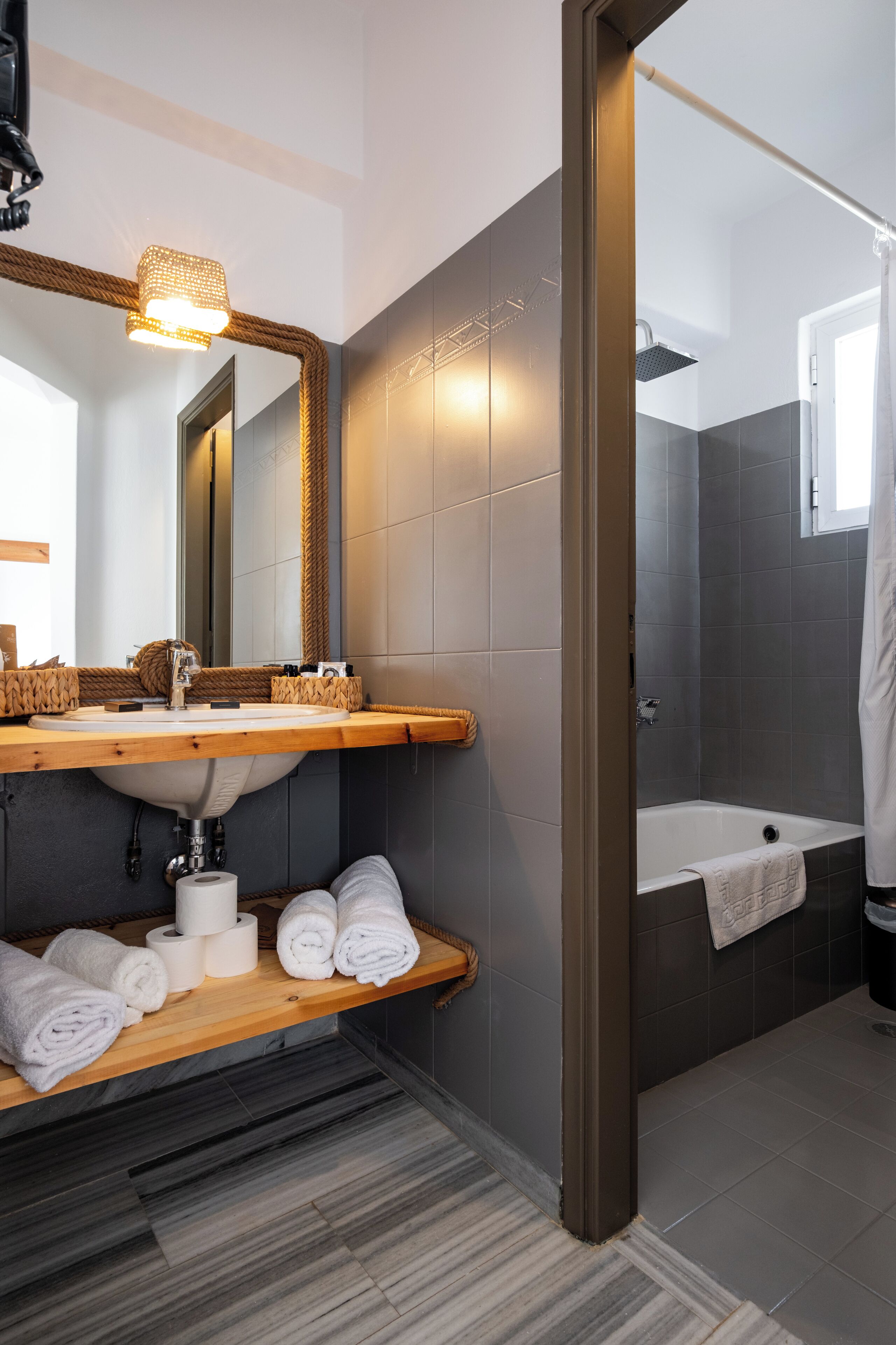 A modern bathroom with a wooden vanity, a large mirror, a towel rack, and a bathtub.