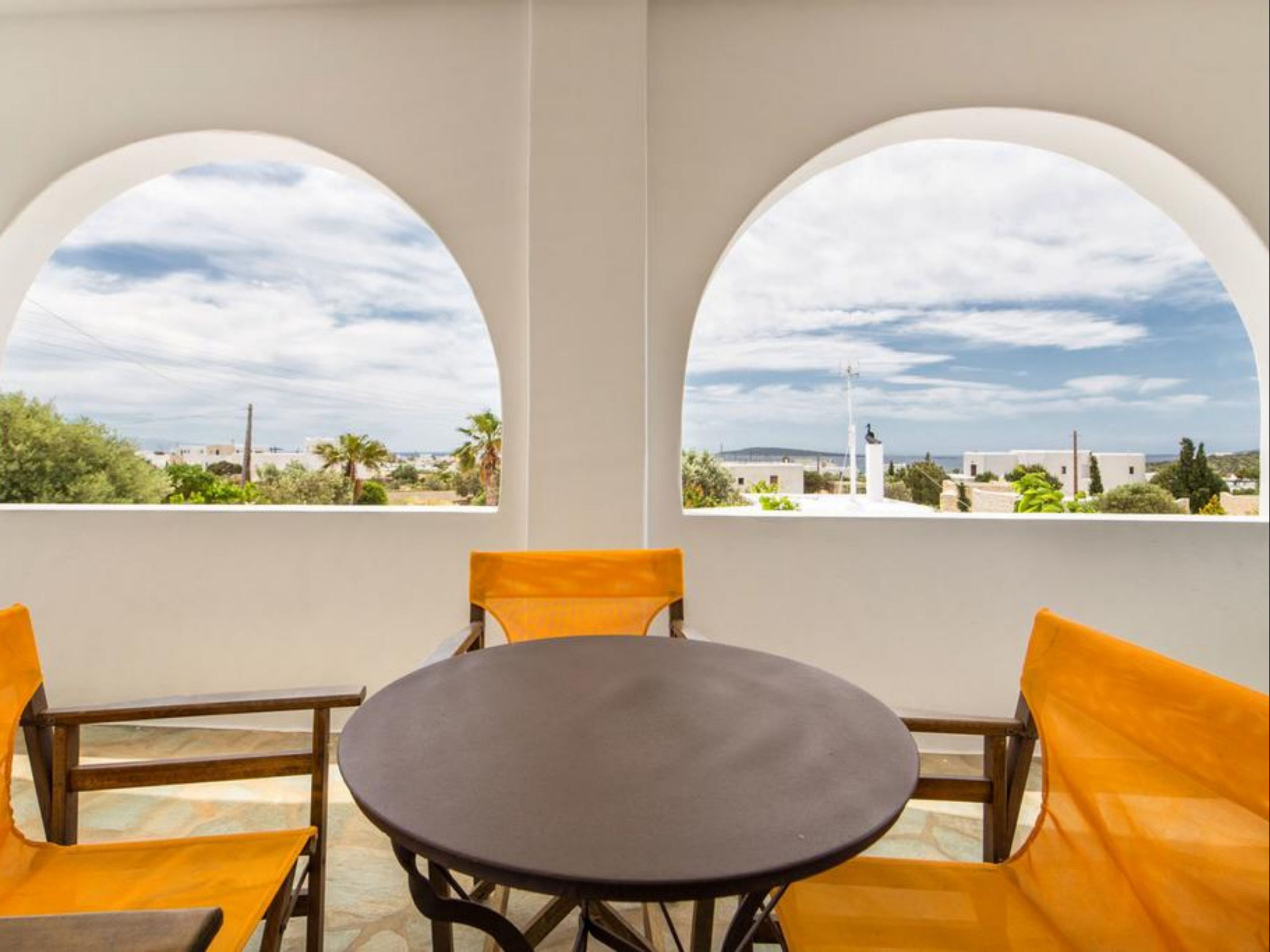 A room with two arched windows, a round table, and two yellow chairs.