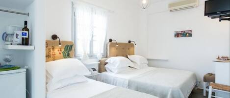 A hotel room with two beds, a small table, a chair, a TV, and a window with curtains.