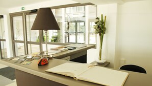 Een receptiebalie met een lamp, een vaas met bloemen en een boek.