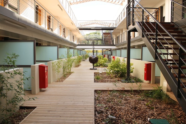 En modern byggnad med en central innergård, träpromenader och en röd elcentral.