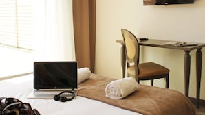 Een hotelkamer met een bed, een bureau, een stoel, een laptop en een televisie.