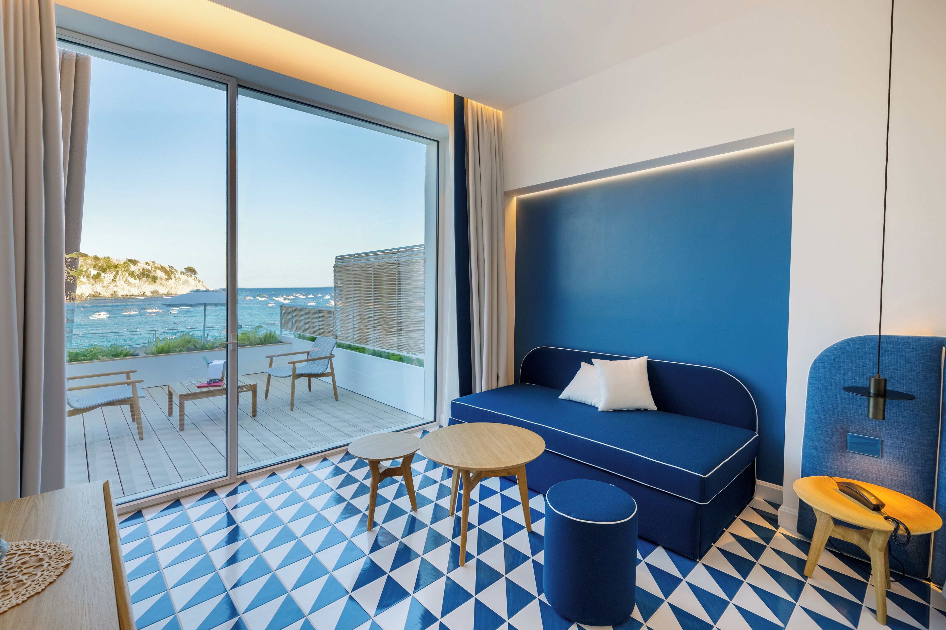 Una habitación moderna con un ventanal grande, un sofá azul y un suelo estampado.