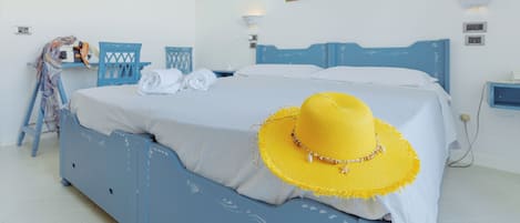 A bedroom with a bed, a yellow hat, and a painting on the wall.