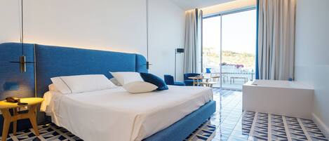 Una habitación de hotel moderna con una cama grande, una mesita, un sofá y vistas al exterior.