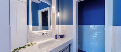 A modern bathroom with a white sink, blue walls, and a large mirror.