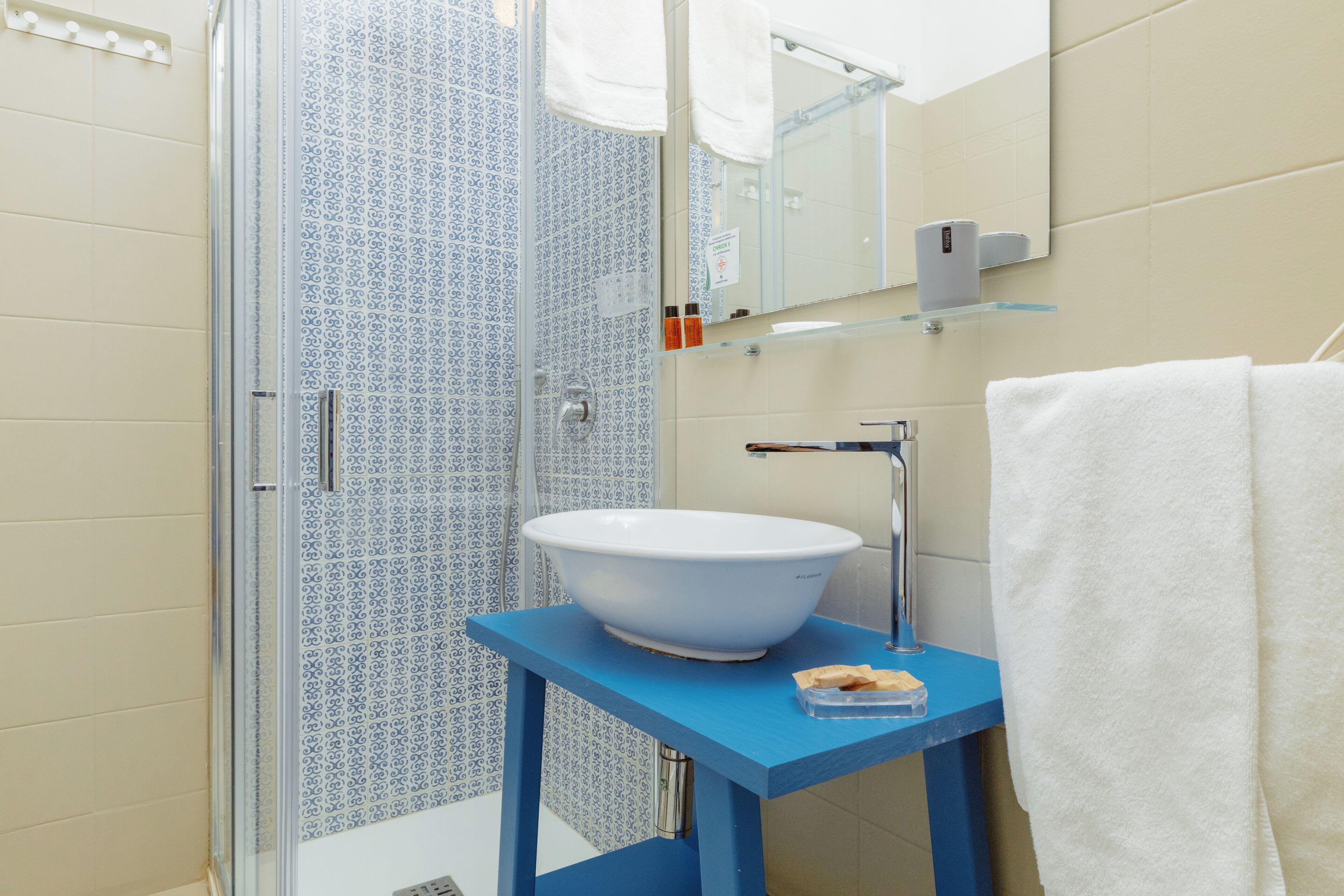 Une salle de bain avec un meuble-lavabo bleu, un lavabo blanc et une cabine de douche en verre.
