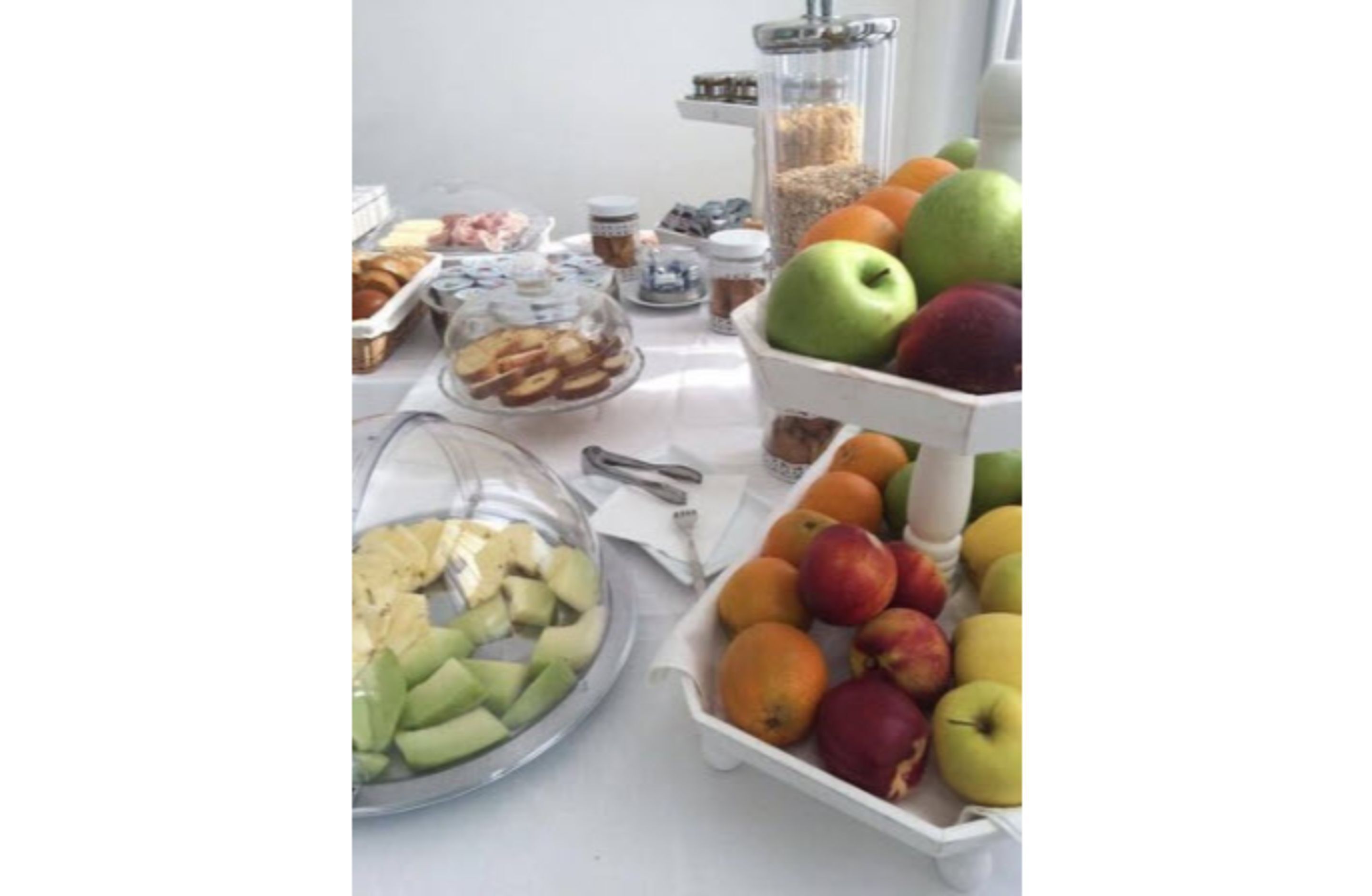 Een ontbijtbuffet met diverse soorten fruit, gebak en toevoegingen.