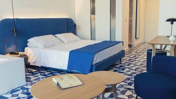 Een moderne hotelkamer met een bed, een klein tafeltje, een stoel en een bureau met een lamp.