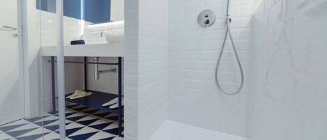 A modern bathroom with a geometric patterned floor, a shower with a handheld hose, and a visible sink area.