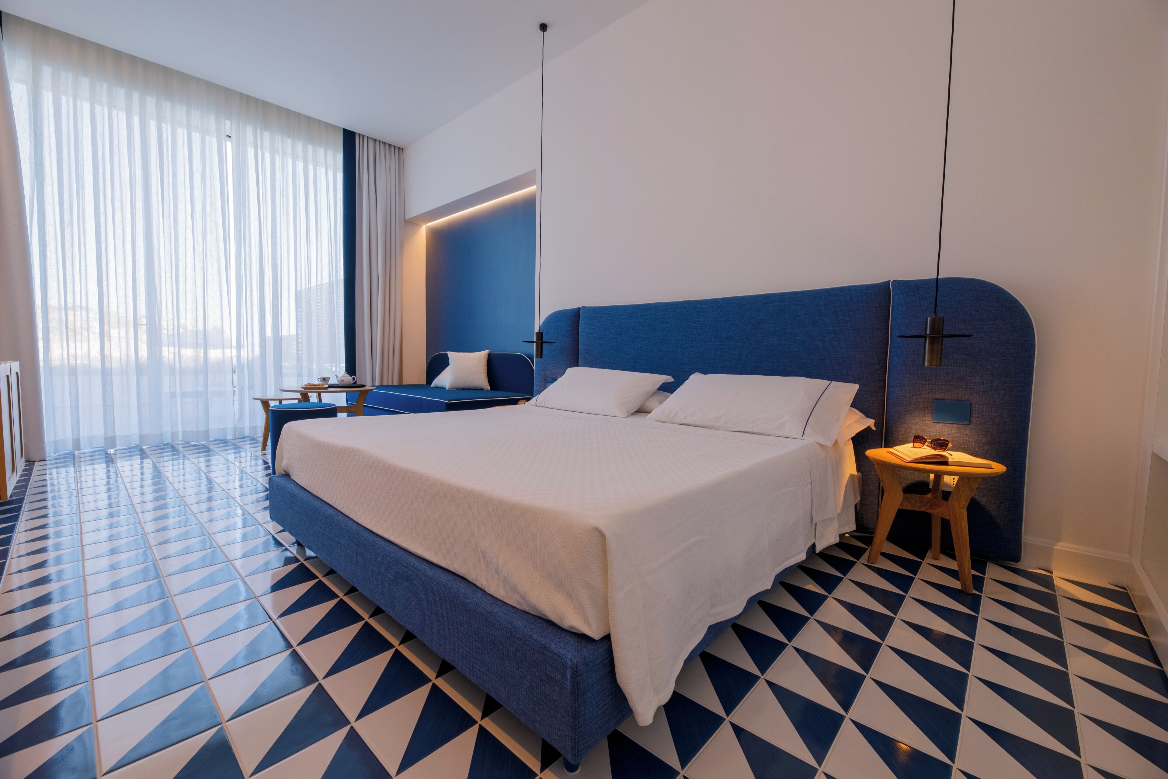 Una habitación de hotel moderna con una cama grande, una mesita y una silla.