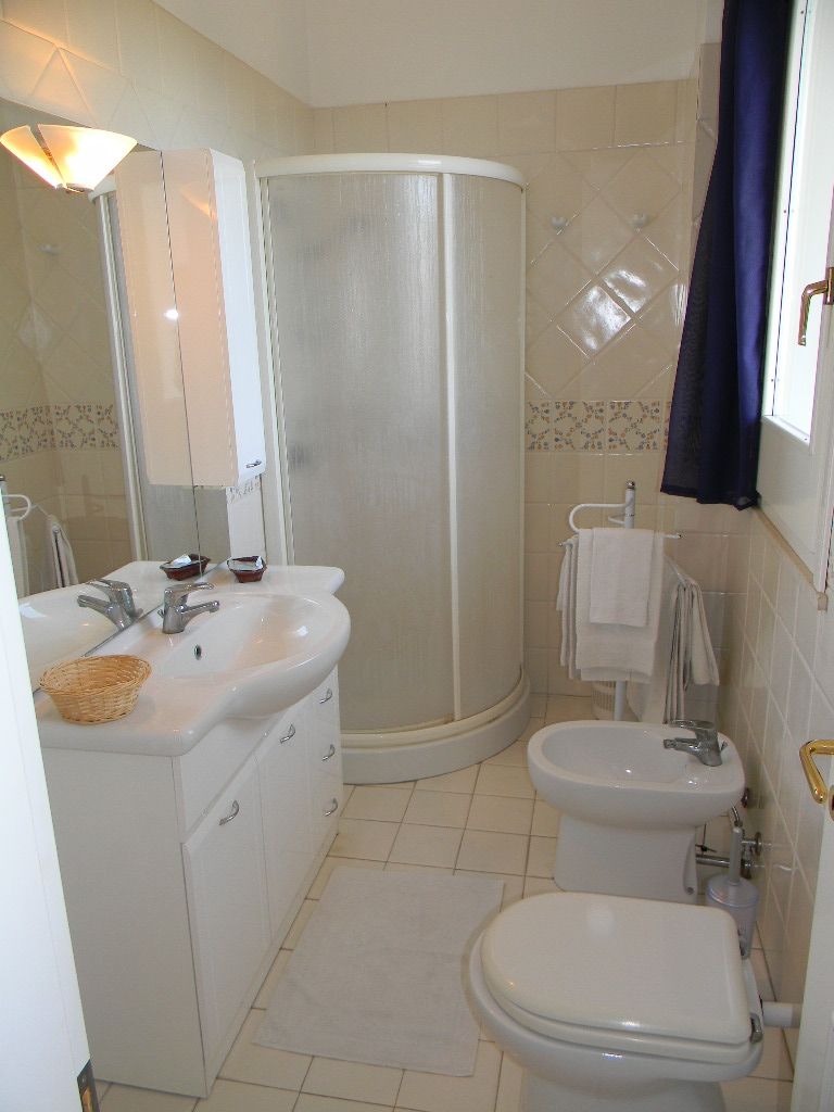 Ein Badezimmer mit Dusche, zwei Waschbecken, Toilette und Spiegel.