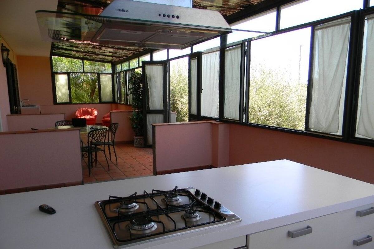 A kitchen with a gas stove, a ceiling fan, and a window overlooking a garden.