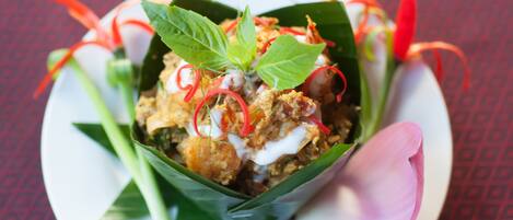 A dish in a leaf bowl with green leaves, red chili, and white sauce.