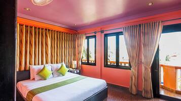 A hotel room with a bed, curtains, a window, and a balcony.