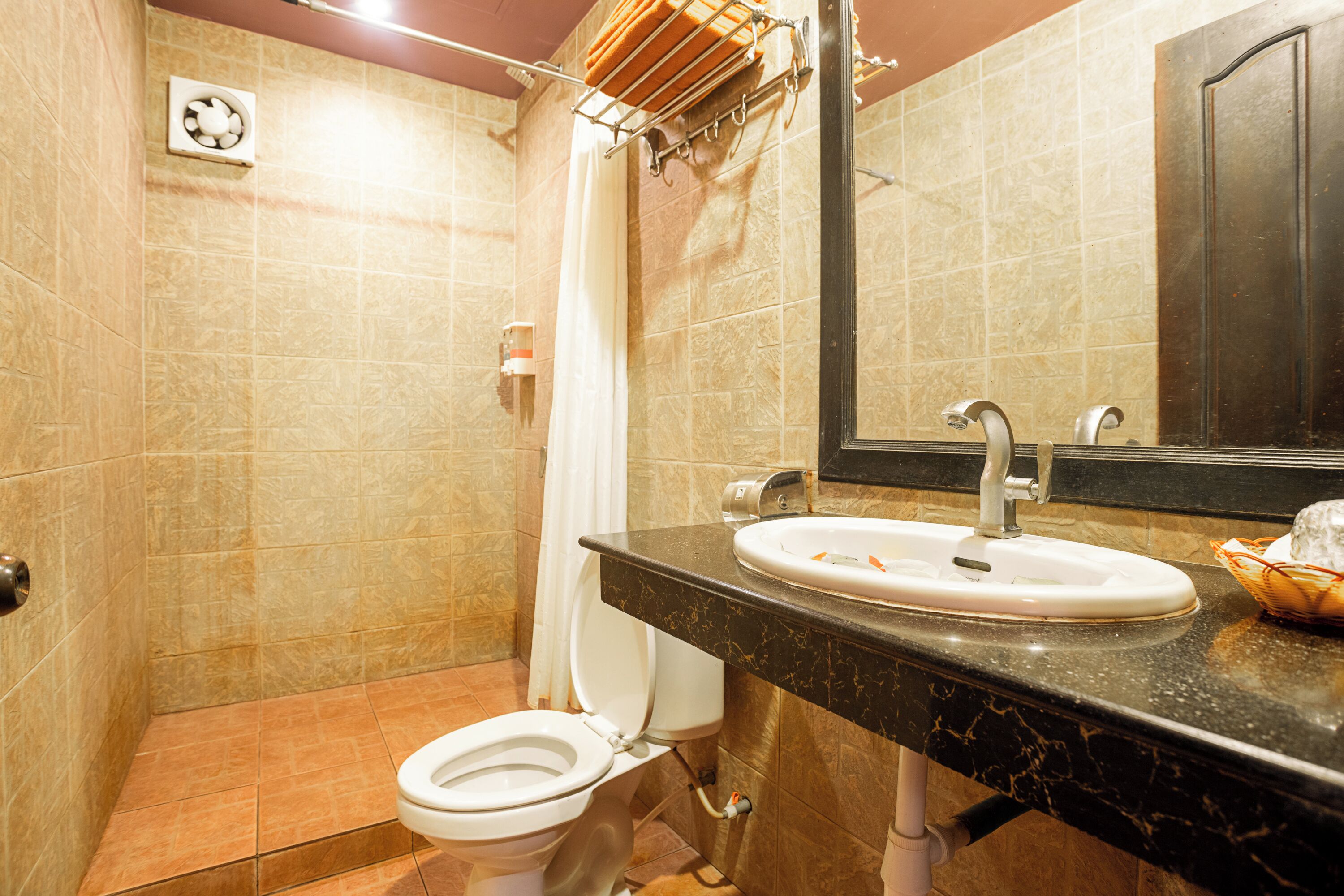 Un bagno con WC, lavandino, specchio, porta asciugamani e tenda doccia.