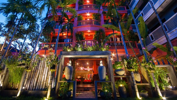 A multi-story hotel with balconies, palm trees, and a well-lit entrance. - Golden Butterfly Villa (Siem Reap)