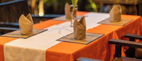 A table set with folded napkins, a vase with a plant, and a tablecloth.