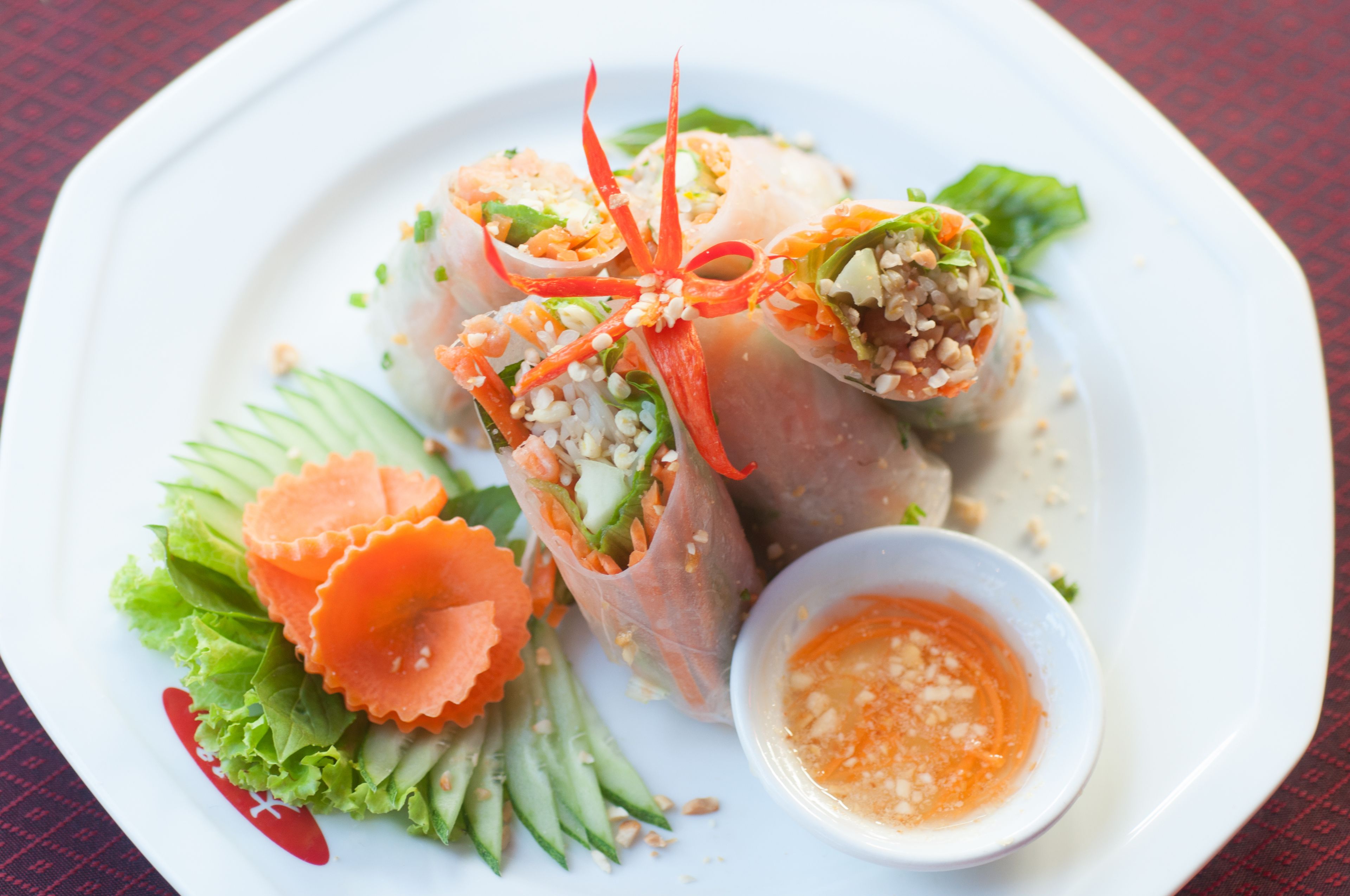 A plate with spring rolls, cucumber slices, and a small bowl of sauce.