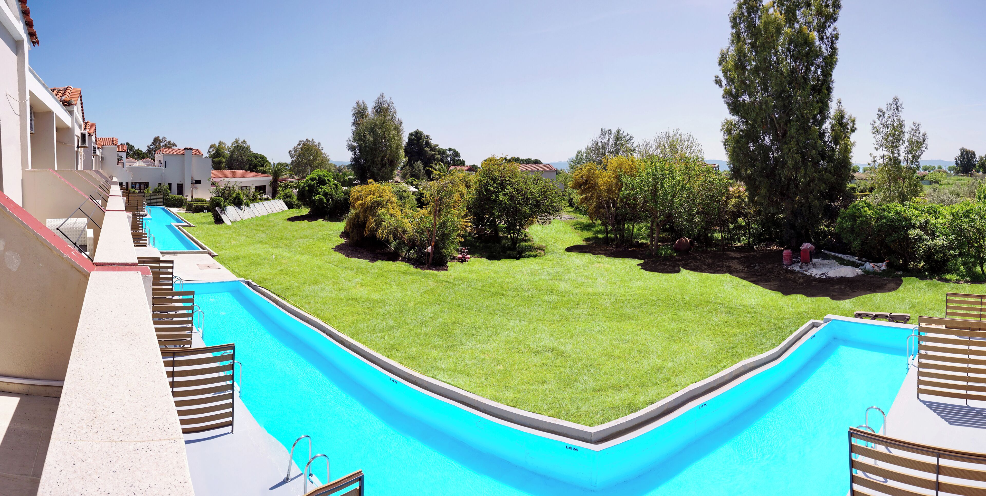 A swimming pool with a clear view of the surrounding landscape, including a grassy area and trees.