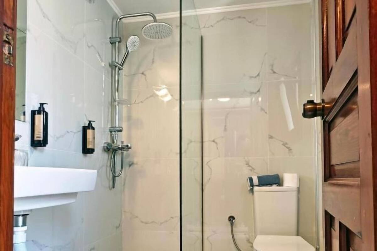 A bathroom with a glass-enclosed shower, a white toilet, and a sink with toiletries.
