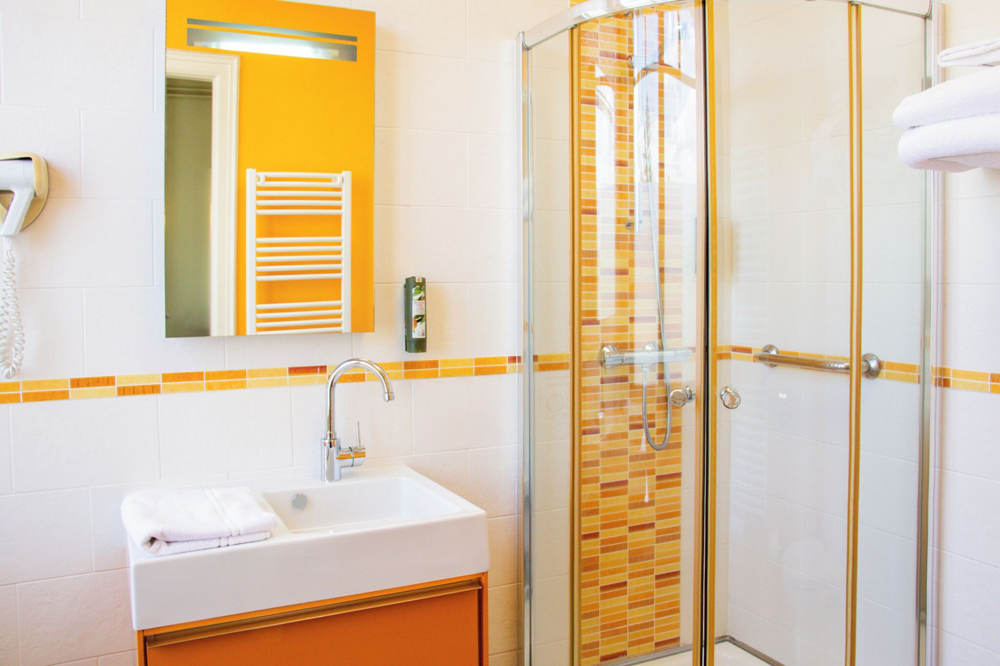 A bathroom with a white sink, a glass-enclosed shower, and a mirror above the sink.