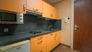 A kitchen with a microwave, stove, sink, and orange cabinets.