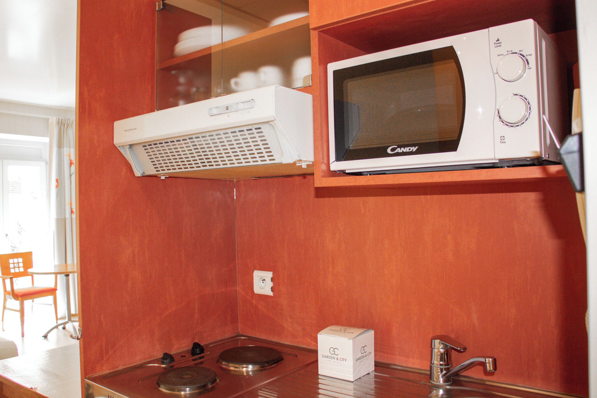 A compact kitchenette with a microwave, a small stove, and a sink.