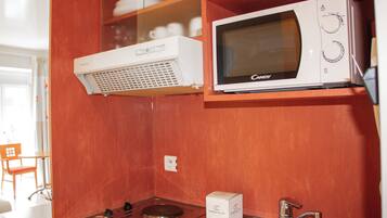 A compact kitchenette with a microwave, a small stove, and a sink.