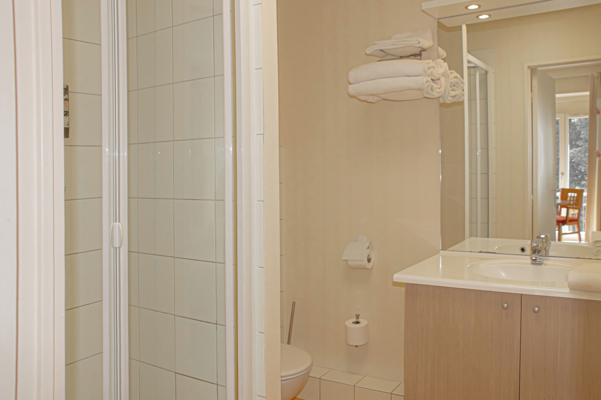 A bathroom with a shower, toilet, sink, and towels on the wall.