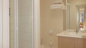A bathroom with a shower, toilet, sink, and towels on the wall.