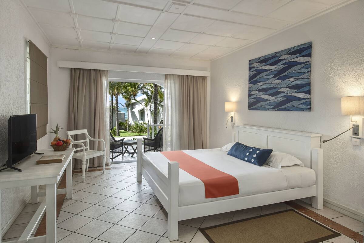 A hotel room with a bed, a desk, a television, and a view of the outdoors.