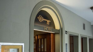 Ein Hotel mit Eingangsbereich, einem schlüsselartigen Schild über der Tür, einem Empfangstresen und einem Korridor zu den Zimmern.