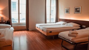 Ein Hotelzimmer mit zwei Betten, einem Schreibtisch und einem Fenster mit Vorhängen.