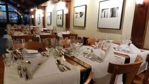 Ein Restaurant mit mehreren gedeckten Tischen, alle mit weißen Tischdecken, Besteck und Weingläsern.