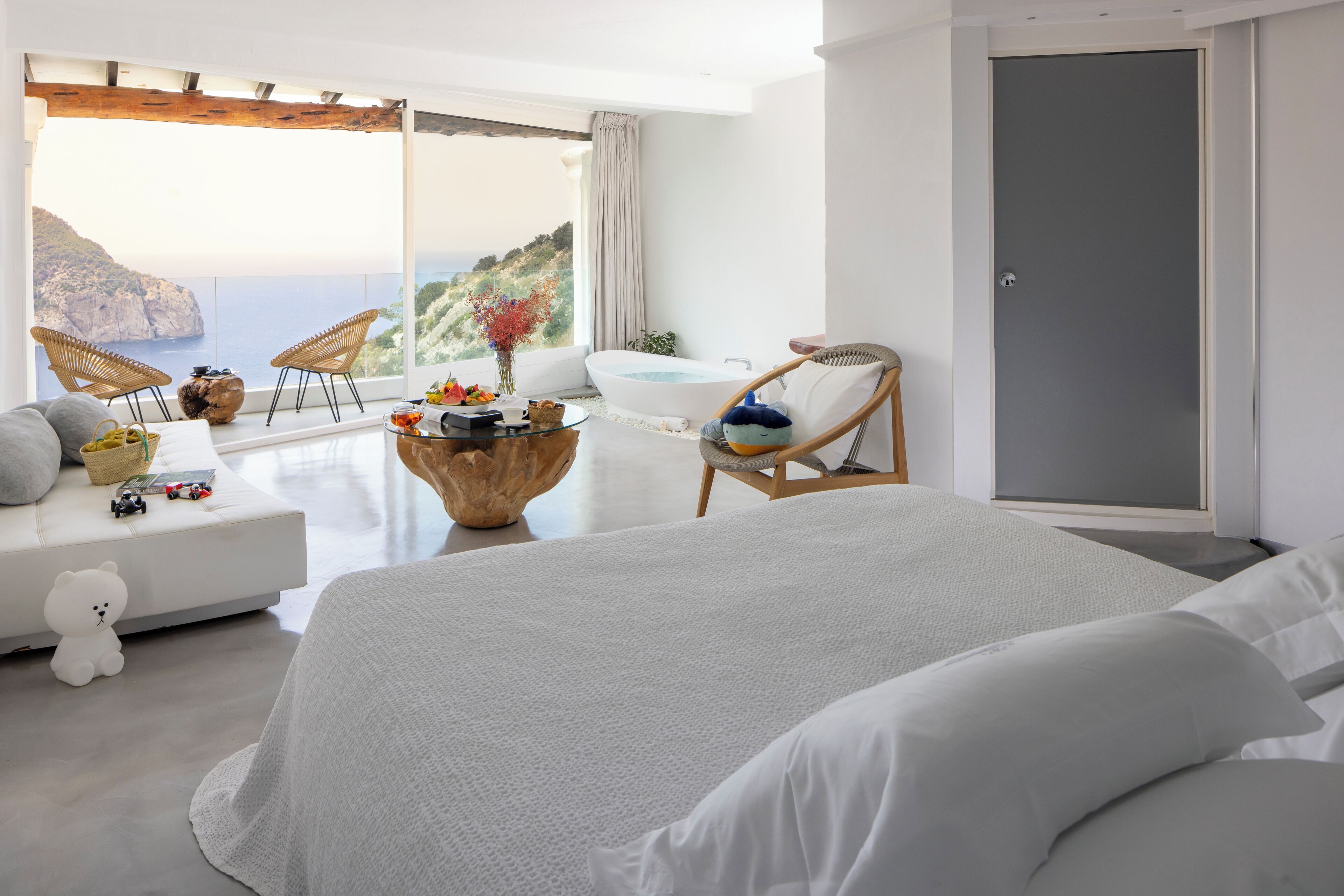 Una camera da letto con un letto grande, un angolo salotto con vista sul mare e una vasca da bagno.