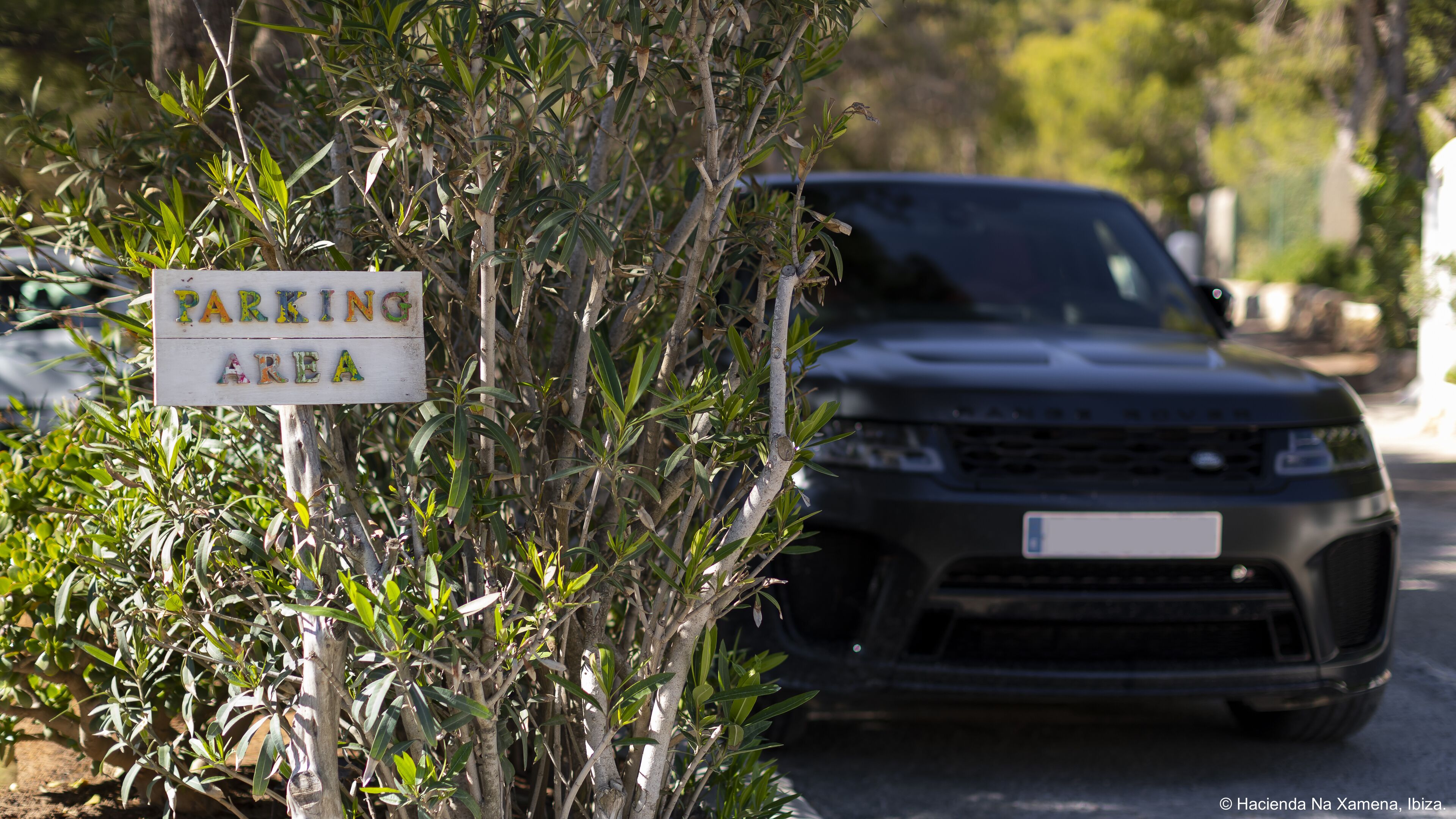 A sign indicating a parking area with a vehicle parked nearby.