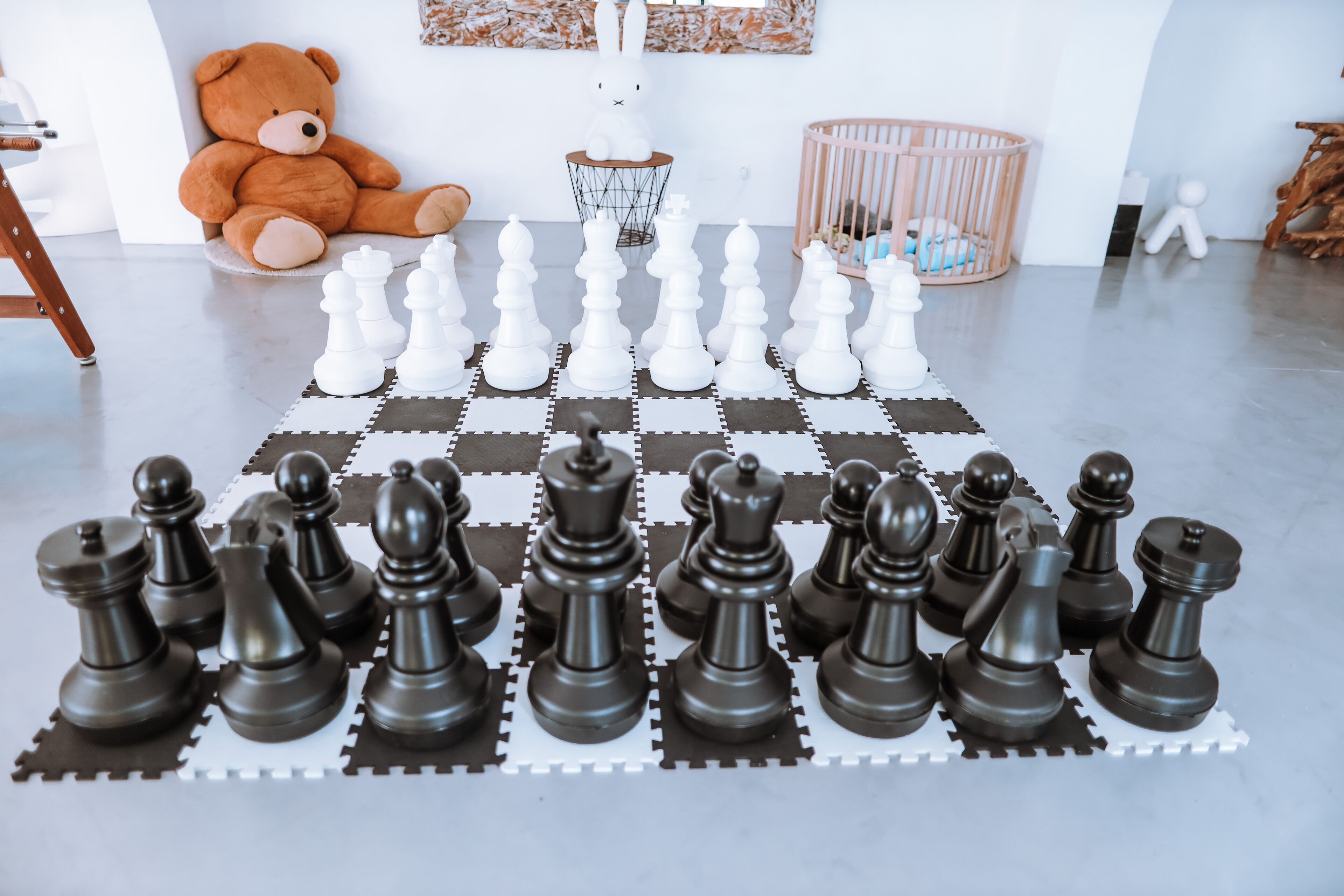 A checkered floor with chess pieces arranged in two rows.