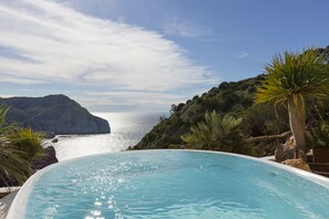 Une piscine avec vue sur l’océan et les collines.